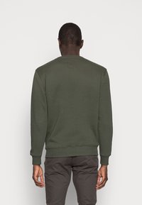 Groene sweatshirt met een ronde halslijn, ribgebreide boorden en zoom, en een rechthoekig label aan de achterkant. Zacht stof met een gladde textuur.