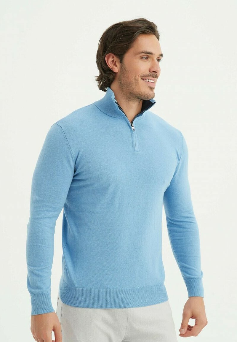 Sweater zippé bleu clair en tissu doux, doté d'un col montant et de poignets côtelés. Coupe ajustée avec des manches longues et une texture lisse.