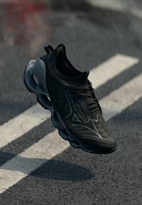 Black athletic shoe with a textured upper, lace closure, and a unique segmented midsole, showcasing a smooth finish and sleek design.