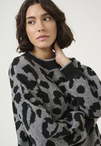 Maglione grigio con stampa leopardata nera. Caratterizzato da un collo girocollo, maniche lunghe e polsini a coste. Tessuto morbido e vestibilità rilassata.