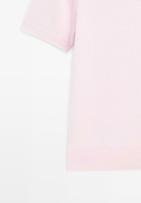 Maglione rosa chiaro a maniche corte realizzato in morbido tessuto a maglia. Presenta un orlo e polsini a costine, con una consistenza liscia.