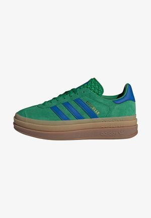 Grüner Adidas Gazelle Sneaker aus Wildleder mit blauen Streifen und Ferse, gestapelte Gummisohle und geprägtem Branding an Seite und Sohle.