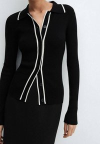 Cárdigan negro de canalé con borde blanco, de manga larga y seis botones frontales, con un diseño de cuello clásico.