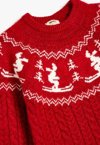 Maglione rosso lavorato a maglia con design a treccia, colletto rotondo e motivi di coniglietti da sci bianchi con alberi lungo la spalla.