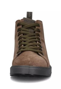 Sneaker in suede marrone con suola in gomma nera, lacci verdi e occhietti metallici. Presenta un logo sulla linguetta e un occhiello sul retro.