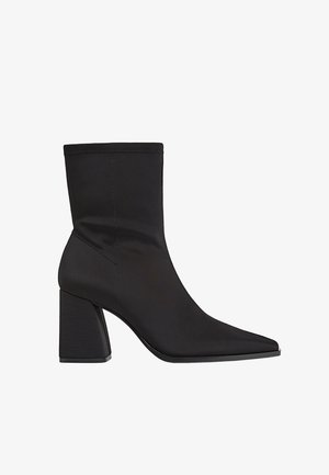 Bottes noires à chevilles en tissu lisse, avec un bout pointu, un talon bloc et un design sans couture avec des détails de couture subtils.
