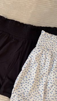 To par kvinnereshorts: ett par svarte med smock-liv og et par hvite med blå blomster mønster, myk stoff, og løs passform.