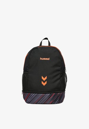 Sac à dos Hummel noir et orange avec poches latérales en maille, double logo chevron orange, et fond à motifs rayés noir, gris et rouge.