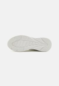 Weiße Sportschuhsohle mit strukturiertem Grip-Muster und geometrischen Formen. Leicht erhöhte Bereiche bieten Halt und Unterstützung.
