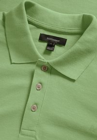 Ljusgrön pikétröja med texturerad tyg, tre beige knappar och ribbat krage. Etikett visar "Matinique," storlek L.