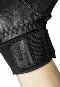 Black leather glove showing a textured wrist area with a smooth, stitched design and a velcro strap for adjustment.