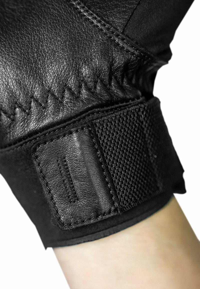 Black leather glove showing a textured wrist area with a smooth, stitched design and a velcro strap for adjustment.