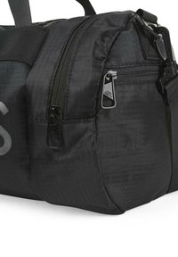 Bolsa de viaje negra hecha de tela texturizada, con múltiples bolsillos con cremallera, asas resistentes y un logotipo sutil en el lateral.