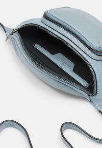 Borsa in pelle azzurra con apertura con zip, dotata di un interno nero, tracolla sottile e una tasca interna.