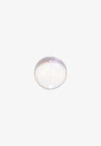 Goccia di gel chiara e rotonda con piccole bolle d'aria all'interno su sfondo bianco, che mostra una texture liscia e traslucida.
