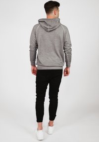 Grå hoodie med en strukturerad huva, ribbade ärmslut och nederkant. Parat med svarta slim-fit byxor och vita sneakers.