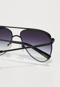 Sorte aviator solbriller med gradient grå linser. Tynn metallramme med dobbel brodesign. Teksturerte armer har "Le Specs" merkevare.