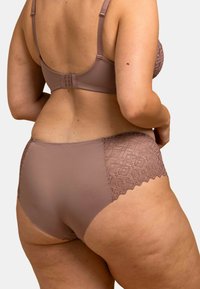 Ensemble soutien-gorge et culotte en mauve clair. Le soutien-gorge présente une texture lisse avec des bretelles réglables ; la culotte a un côté en dentelle avec un motif géométrique et des bords festonnés.