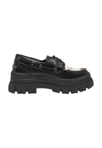 Mocassin en cuir noir à semelle épaisse à crampons, lacets à l'avant et panneau blanc à motifs sur le dessus.