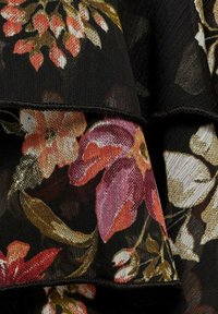 Tessuto con motivo floreale caratterizzato da fiori multicolori in tonalità di rosa, arancione e giallo su uno sfondo nero con un bordo a volant stratificato.