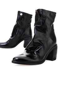 Botines de cuero negro con un diseño arrugado, puntera afilada y tacón de bloque. Presentan una cremallera lateral y una textura suave.