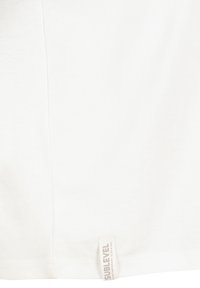 White cotton t-shirt with a soft texture, short sleeves, and a small label stitched at the bottom displaying "SUBLEVEL" in light gray.