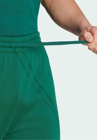 Green elastic waist joggers with a drawstring. The fabric is soft and smooth, featuring a gathered waistband for adjustable fit.