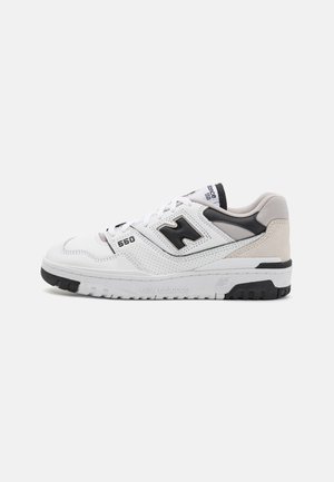 Valkoinen ja musta New Balance 550 -tossu, jossa on rei'itetty nahka, mokkanahkainen kantapää ja brändätty pohja, kuvattuna sivuprofiilissa.
