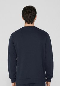 Marineblaues Sweatshirt mit Rundhalsausschnitt, langen Ärmeln und gerippten Bündchen und Saum. Glatte Textur, schlichtes Design und ohne sichtbare Muster.