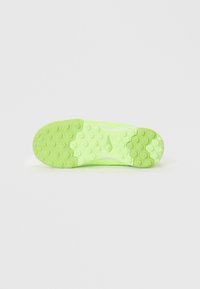 Suela de zapatilla deportiva verde brillante con patrón de agarre texturizado hexagonal y logotipo central sobre un fondo blanco liso.