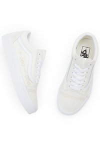 Bílé plátěné tenisky s texturovaným vzorem, mají bílou gumovou podrážku a tkaničky, a kontrastující boční akcenty s embosovaným designem.