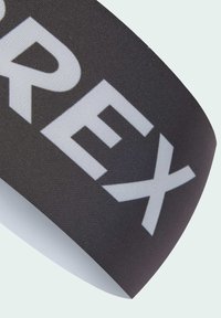 Čierna elastická povraz so veľkým bielym textom "REX." Text je tučný a rozprestiera sa po povrchu pásky. Hladký povrch, mierny lesk.