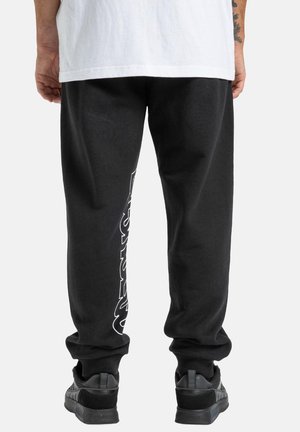 Schwarze Jogginghose mit lockerer Passform, mit weißen grafischen Texten entlang des linken Beins. Rippbündchen und elastischer Bund; aus weichem Material hergestellt.
