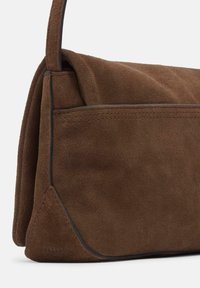 Borsa a spalla in suede marrone con chiusura a pattina, rifiniture nere e dettagli di cucitura, in vista laterale con tracolla.