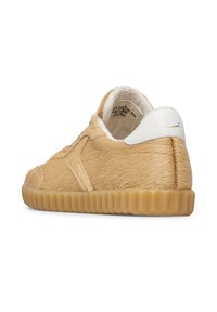 Sneaker a basso profilo con texture in pelliccia beige, suola in gomma e tab sul tallone bianco, inclinato per mostrare i dettagli del lato esterno e del retro.