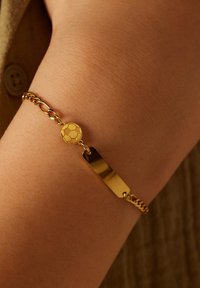 Gouden kettingarmband met een textuur charm in de vorm van een voetbal en een gladde, rechthoekige schakelkette. Het heeft een gepolijste afwerking en een verfijnd ontwerp.