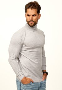 Light gray turtleneck sweater in soft knit. Fitted design with long sleeves and ribbed cuffs. Paired with blue denim jeans.