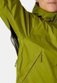 Zielona wodoodporna kurtka z zamkiem błyskawicznym w bocznej kieszeni, kapturem i elastycznymi mankietami. Materiał wydaje się lekki o gładkiej fakturze.