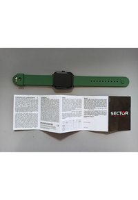 Orologio smartwatch in silicone verde con quadrante nero quadrato. Accompagnato da un manuale utente piegato con testo bianco e copertina nera con il logo "SECTOR".