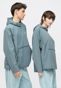 Letvægts, hættetrøje i skiferblå med forlomme og halvlukning med lynlås; glat tekstur og afslappet pasform.