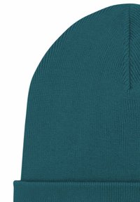 Cuffia a maglia turchese con risvolto arrotolato. Presenta una texture liscia e una costina fine, con una sommità arrotondata. Nessun motivo o elemento metallico visibile.