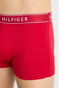 Piros pamut boxer nadrág fehér logószőtt anyaggal, amelyen a "HILFIGER" felirat található. Simaszerkezet és testhez simuló fazon, kiemelt varrási részletekkel.