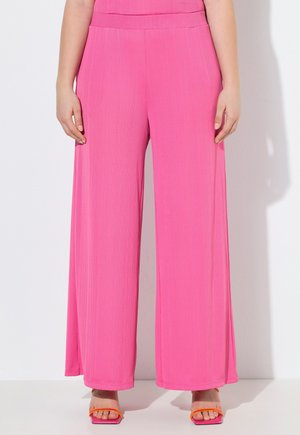 Lyserøde bukser med høj talje og vide ben, med en subtil lodret tekstur, båret med orange hælsandaler med rem, vist fra talje til fødder.