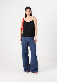 Top de tanque negro con pliegues, jeans anchos de mezclilla azules y bolso rojo. Los jeans tienen una textura clásica de mezclilla, mientras que el top cuenta con tirantes delgados.