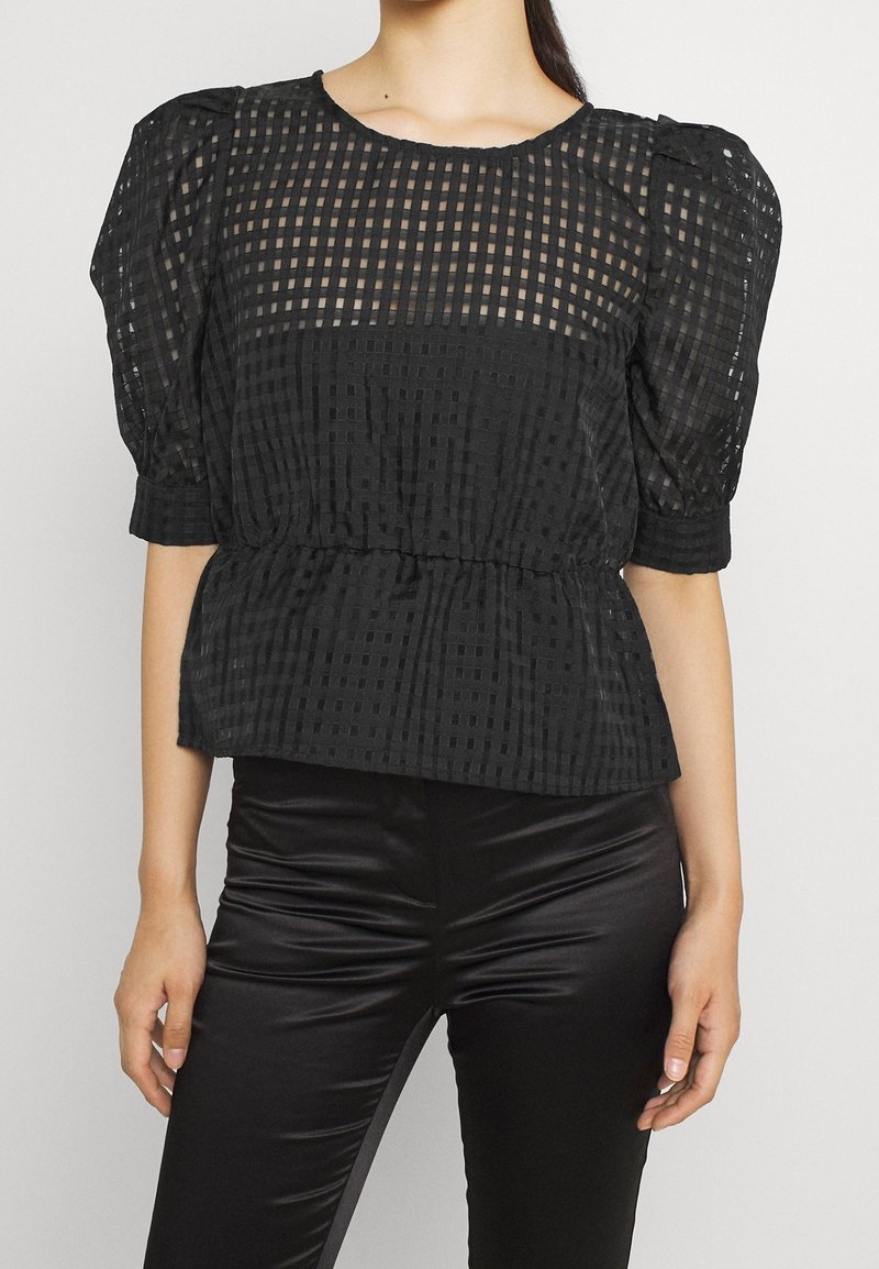 Blusa nera con maniche a palloncino, caratterizzata da un motivo a rete testurizzato, vita aderente e parte superiore in tessuto trasparente con scollatura rotonda.