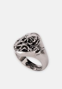 Sølvfarget ring med et detaljert hodeskalle-design, med flytende aksenter, polert overflate og tykk ring.