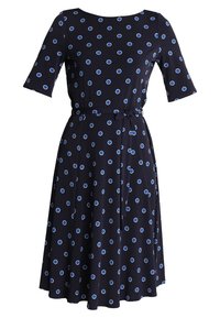 Mörkblå klänning med korta ärmar, prydd med blå prickar. Inkluderar ett midjebälte för form och en flödande kjoldesign.