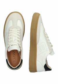 Sneakers bianchi realizzati in materiali scamosciati e in pelle, con punta rotonda, suola in gomma, accentuazione nera sul tallone e dettagli perforati sul lato.
