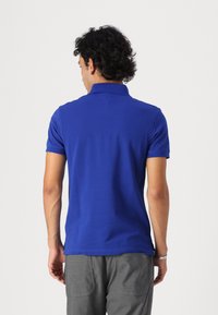 Camisa polo de manga corta para hombre en azul brillante, hecha de tejido suave, con un cuello estándar y sin patrones ni logotipos visibles.