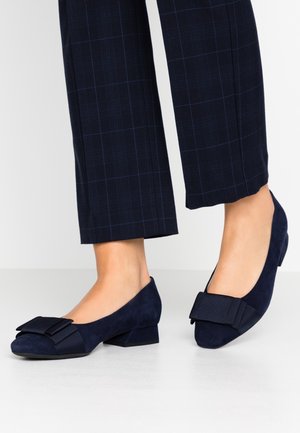Granatowe zamszowe baleriny z kokardką na palcach, zaokrąglony kształt i niski słupkowy obcas, zestawione z ciemnym wiskozowym materiałem w kratę.